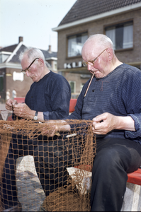 852321 Afbeelding van vissers tijdens het boeten van de netten in de haven van Spakenburg.